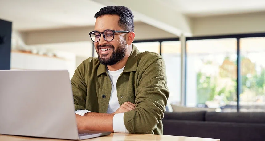 Man smiling while working on a laptop